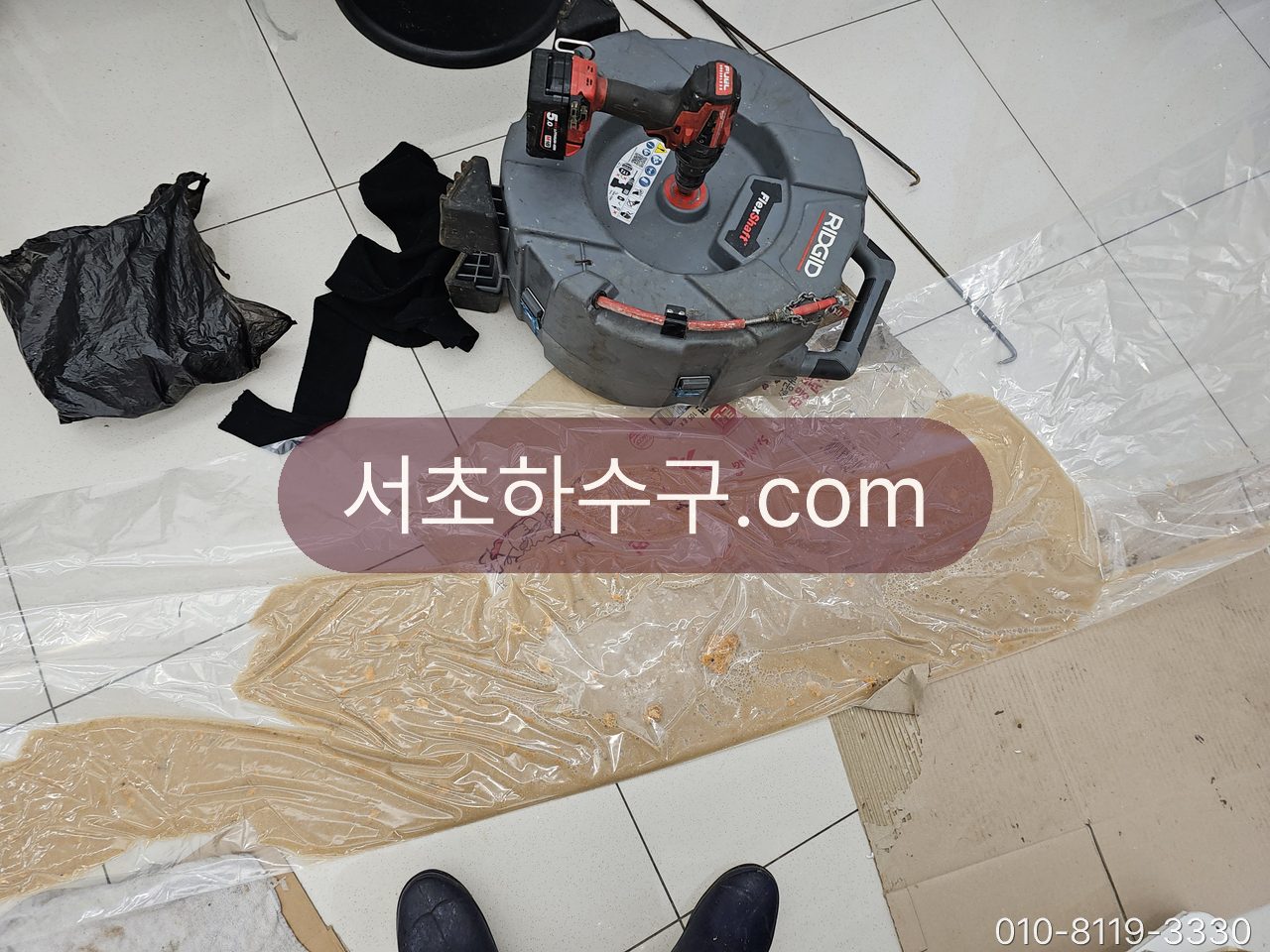 상가 바닥에 깐 비닐 위로 세척 장비가 관 벽에서 벗겨낸 기름 슬러지가 모여 있는 장면