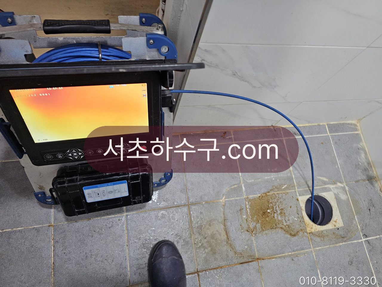 욕실 바닥 배수구에 카메라를 넣고 모니터로 확인하는 장면