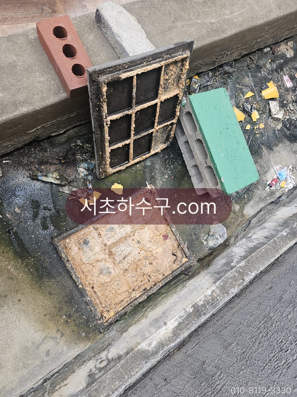 건물 앞 외부 트렌치 배수구 덮개를 열어 퇴적물을 확인하는 모습