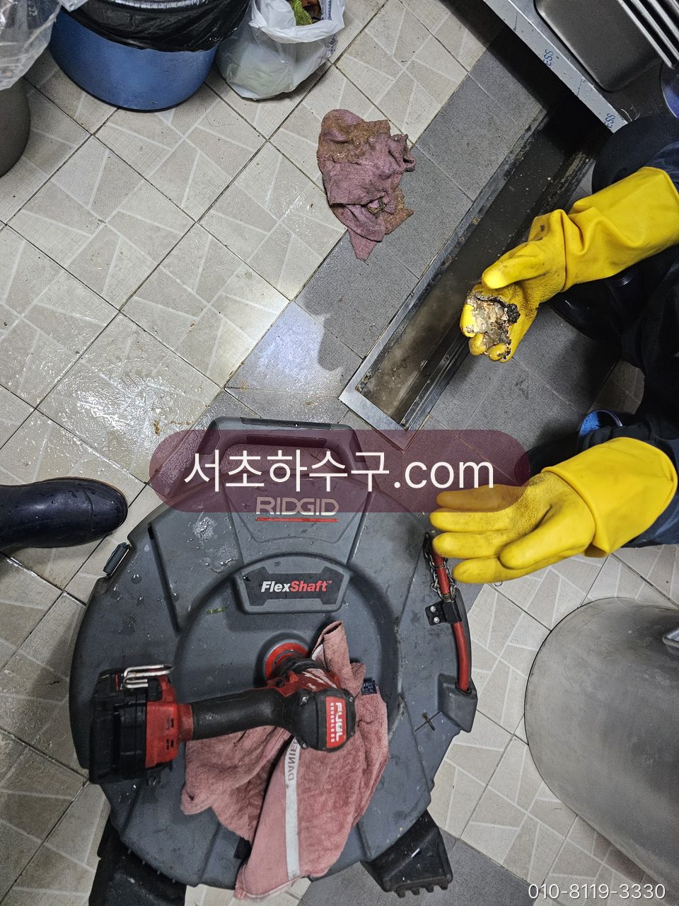 업소 주방 바닥 트렌치 배수구 덮개를 열고 굳은 기름 덩어리를 걷어내는 장면