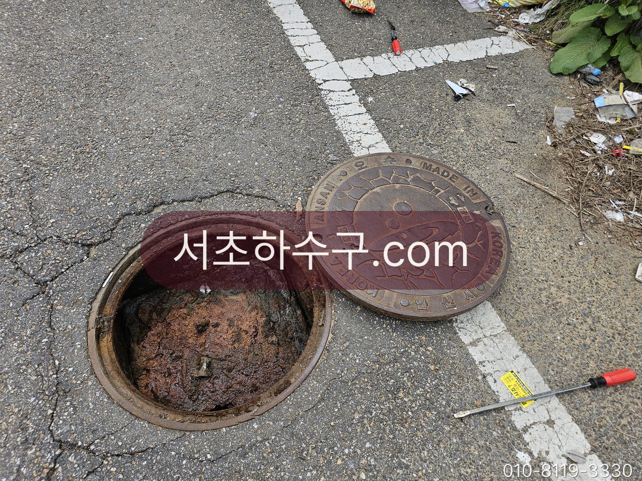 도로변 외부 맨홀 뚜껑을 열어 공용관 상태를 확인하는 장면