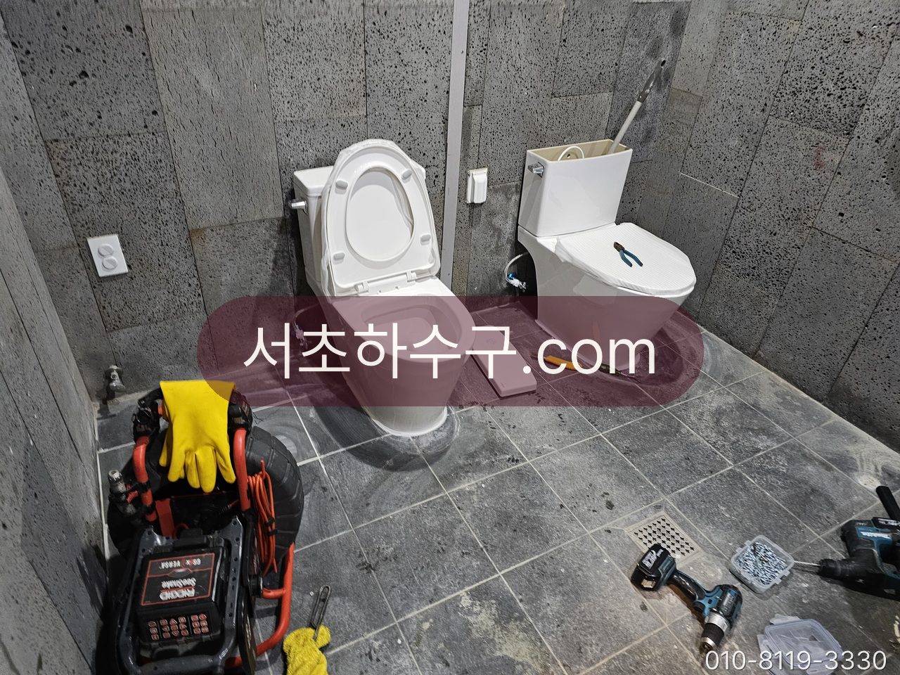 기존 변기 옆에 새 변기가 놓인 교체 작업 중인 화장실